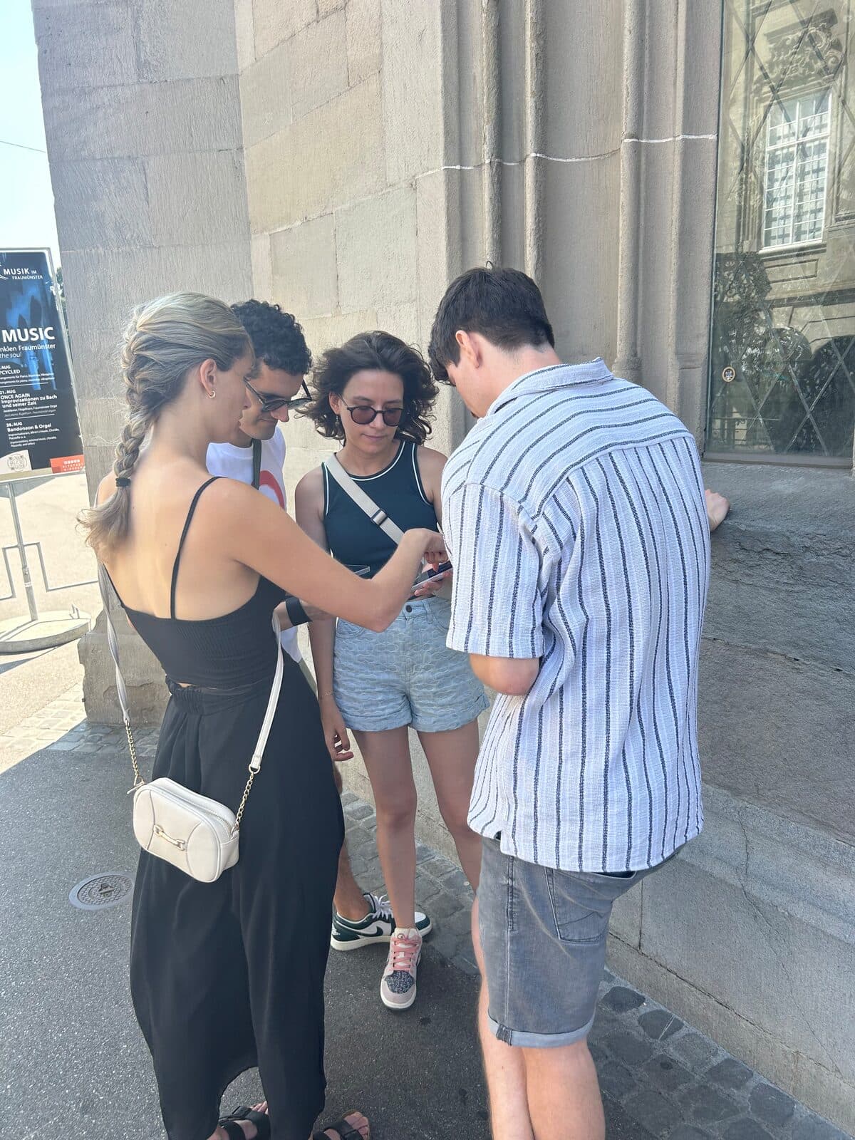 A team huddled over one phone against the stone wall of the Fraumünster, where the quest finishes.